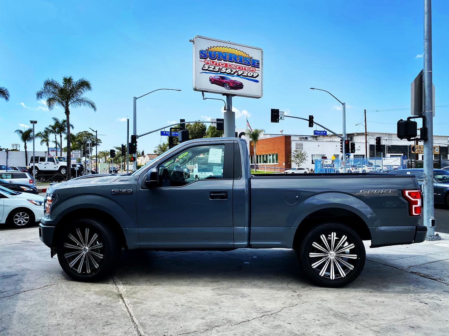 Truck with custom wheels in front of the Sunrise Auto Center sign